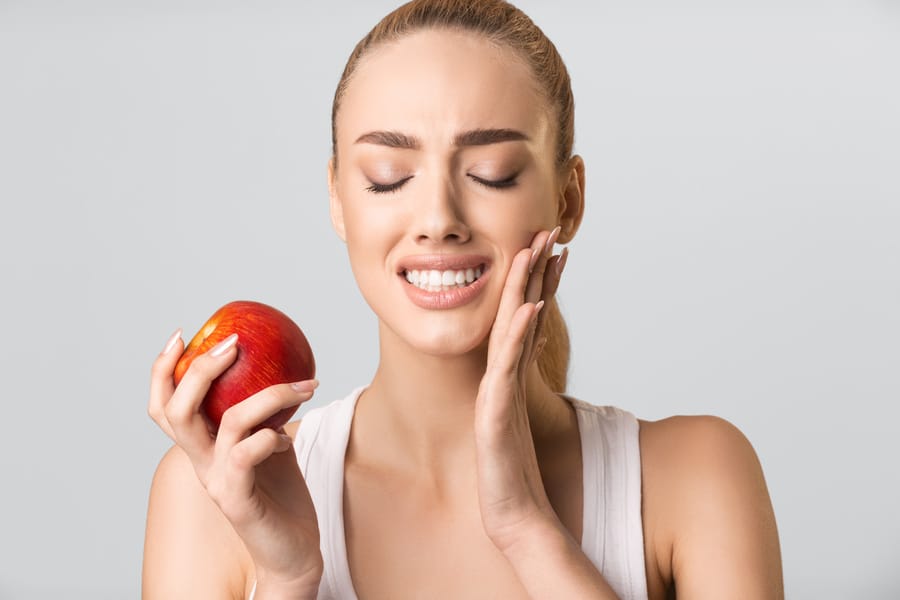 Young Woman Having Tooth Pain Eating Apple On Gray Background Desensitization Ottawa